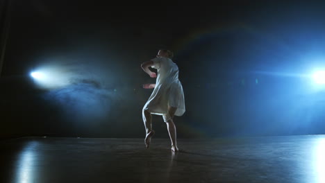 Ein-Junges-Mädchen-In-Einem-Weißen-Kleid-Tanzt-Ein-Modernes-Ballett,-Macht-Drehungen-Und-Sprünge-In-Zeitlupe-Auf-Der-Bühne-Mit-Rauch-Im-Scheinwerferlicht.